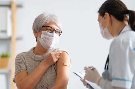 Senior woman after vaccination and her doctor. virus protection. covid-2019. Фото со стока