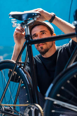 ひげを生やした職人のワーク ショップで彼の新しい自転車を押しながら