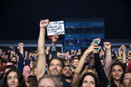 Nyon, switzerland - 27 july 2019 :crowd of audience at concert of french rap singer youssoupha. a man holds a sign saying: we came to clean up the vocabulary in french rap - "on est venu nettoyer le vocabulaire du rap francais" Stock Photo