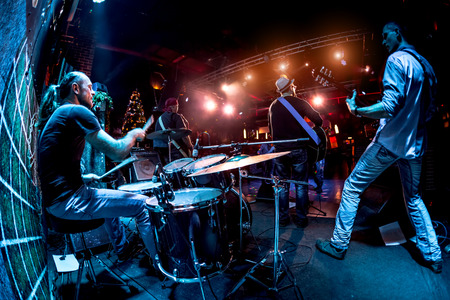 Band performs on stage, rock music concert. Warning - authentic shooting with high iso in challenging lighting conditions. A little bit grain and blurred motion effects.