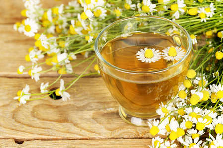 cup of chamomile tea with chamomile flowers on wooden planks