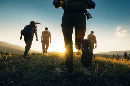 Foto de primer plano de jóvenes excursionistas deportivos caminando en las montañas al atardecer Foto de archivo