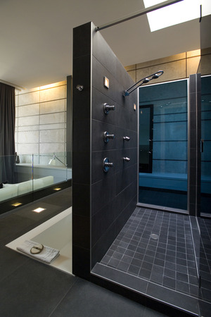 shower with dark grey ceramic walls and floor near the bath stock