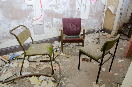 古い摩耗や破損した肘掛け椅子 コンクリートの残骸の中で放棄された建物の腐敗に残されています の写真素材 画像素材 Image