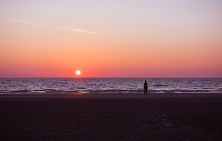 鮮やかな濃い紫色とピンクのロサンゼルスの夕焼け 海岸のゆったりとした静かな日没の夜に散歩をする女性のシルエット の写真素材 画像素材 Image