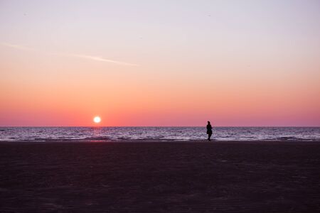 鮮やかな濃い紫色とピンクのロサンゼルスの夕焼け 海岸のゆったりとした静かな日没の夜に散歩をする女性のシルエット の写真素材 画像素材 Image