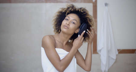 ragazza in bagno bella donna di colore spazzolare i capelli in bagno archivio fotografico