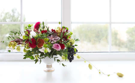 Unusual wedding composition with succulent flowers, grape, fig and hop in retro style near the window