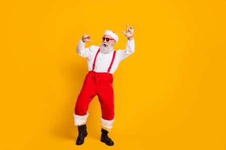 Christmas party hard clubbing. full body photo of cool funky santa claus hipster in red hat enjoy newyear tradition celebration dance wear shirt suspenders isolated yellow color background Stock Photo