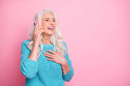Portrait of positive cheerful old woman use smartphone call her friend hear jokes laugh put hands chest wear good look blue jumper isolated over pastel color background