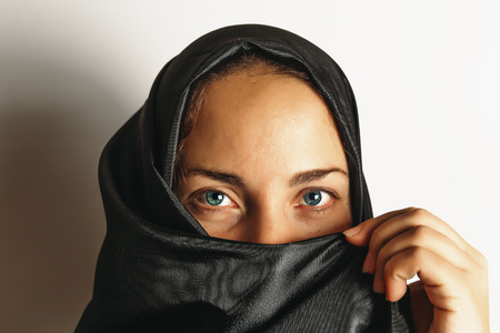 ヒジャーブでイスラム教徒の女性は 肖像画を閉じます 女の子は黒いハンカチで彼女の顔を覆うカメラを見て 明るい青い目 の写真素材 画像素材 Image