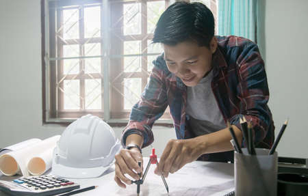 Concept architects engineer holding circus pointing equipment architects on the desk with a blueprint in the office vintage sunset light Stock Photo