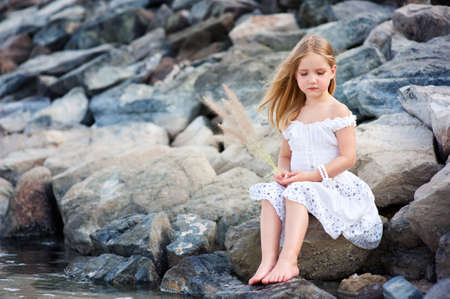 Lonely beautiful girl sitting on stone sea shore and thinking - 14009659