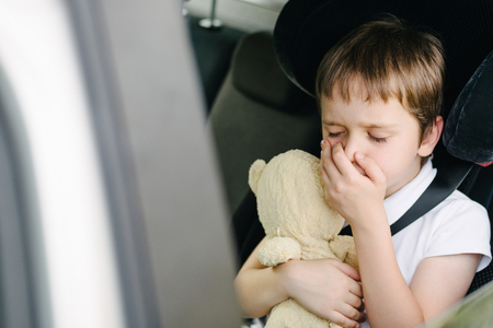 乗り物酔いに苦しんでいる子供安全車の座席に座っている車の後部座席で古い小さな子供 彼の手で彼の口をカバーして 7 年 の写真素材 画像素材 Image