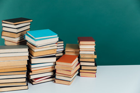 Stacks of old educational books in library on green background