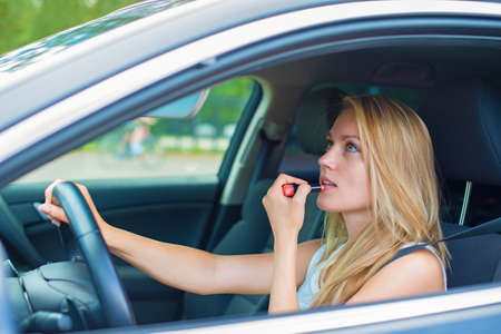美しい若い女性は車を運転中のメイクアップを適用します の写真素材 画像素材 Image
