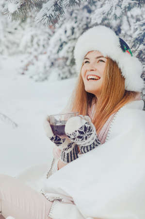 Beautiful girl smiling with a cup of coffee on the background winter forest