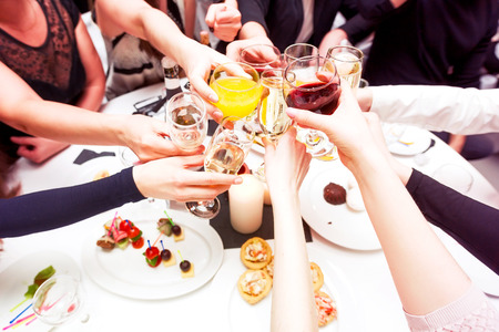 Clinking glasses with alcohol and toasting, party. Congratulations to the event. Cheerful party friends Фото со стока