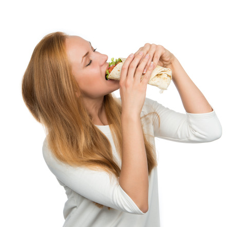 Frau, die geschmackvolles ungesundes Burger verdrehtes Sandwich in den Händen isst, die hungrig sind, das fertig wird zu essen essen lokalisiert auf einem weißen Hintergrund Schnellimbisskonzept