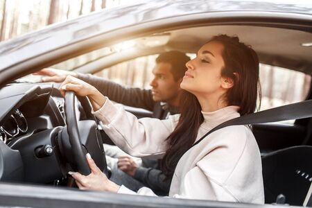 Driving instruction. a young woman learns to drive a car for the first time. her instructor or boyfriend helps her and teaches her