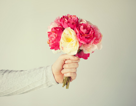close up of mans hand giving bouquet of flowers.