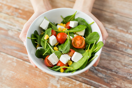 Diäten und Leutekonzept der gesunden Ernährung nah oben von den Händen der jungen Frau, die zu Hause Salatschüssel zeigen