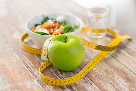 gesund essen Diät Abnehmen und wiegen Verlust Konzept Nahaufnahme von grünem Apfel Maßband und Salat