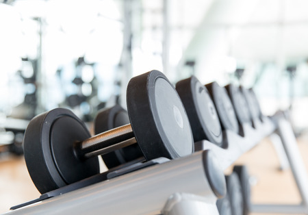 sport, fitness, weightlifting and health care concept - close up of dumbbells in gym