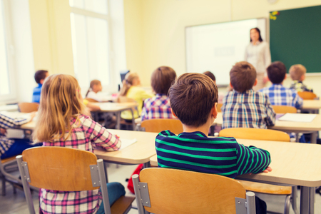 Educazione, scuola elementare, l'apprendimento e la gente il concetto - gruppo di ragazzi delle scuole seduta e l'ascolto di insegnante in aula dal retro Archivio Fotografico - 50369631