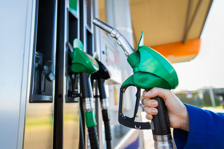 Objeto, combustible, aceite, depósito y transporte concepto - cerca de la mano que sostiene la manguera de la gasolina en la gasolinera Foto de archivo - 51892714