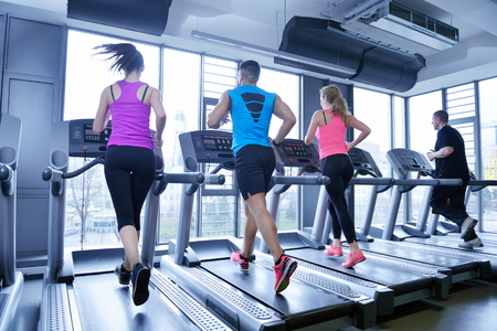 group of young people running on treadmills in modern sport gym