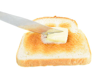 a slice of toast being buttered with a knife isolated on white