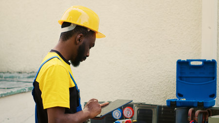 Smiling technician happy with refrigerant levels in external air conditioner while using manifold meters to accurately measure hvac system pressure ensuring optimal cooling performance and efficiency