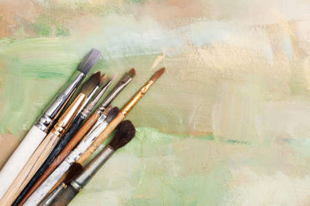 old oil brush lying on a painted canvas expressive base or