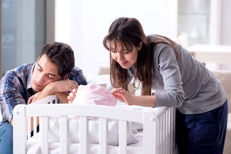 Stock photo young parents with their newborn baby near bed cot Stock photo young parents with their newborn baby near bed cot
