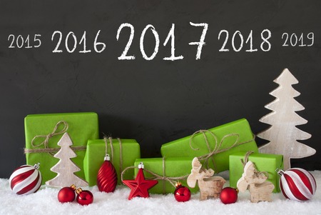 ドイツ語のテキスト Bescherung を意味するギフトを与えます グリーン ギフトやクリスマス ツリー ムースまたは赤のクリスマス ツリーのボールのような装飾をプレゼント 雪を背景として黒セメント壁 の写真素材 画像素材 Image
