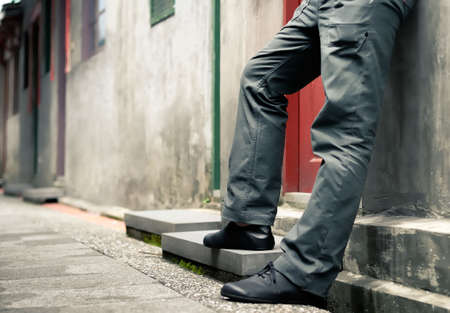 sad lonely: It is mans legs standing against the wall.
