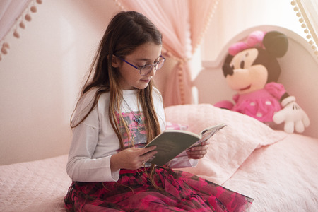 A Child Girl Doing Homework Writing And Reading At Home