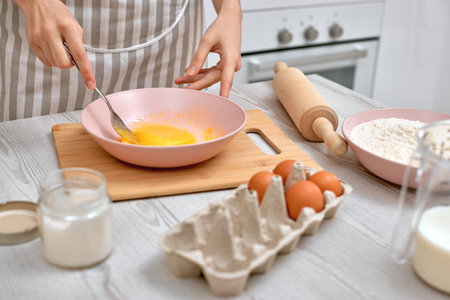 La femme bat des oeufs dans un bol. femme au foyer cuisinant dans la cuisine Banque d'images