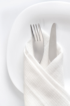 Fork and knife on white plate table setting close up top view