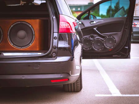 Vue arrière d'une voiture, coffre et porte avant ouverts, avec système audio de voiture installé, haut-parleurs et haut-parleur de caisson de basses géant.
