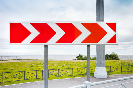 61100160-dangerous-turn-red-and-white-stripped-arrow-road-sign-in-summer-city.jpg