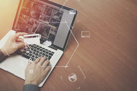 Top view of hand using credit card and laptop computer on wooden desk with vr icon chart graph diagram Stock Photo