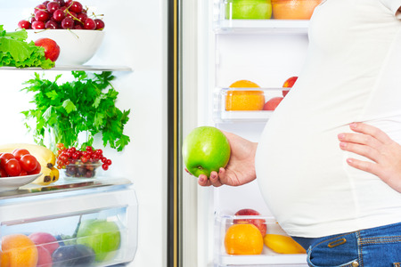nutrition et alimentation pendant la grossesse. Femme enceinte debout près du réfrigérateur avec des fruits et légumes