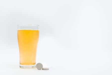 透明なガラスのカルシウムとビタミンC発泡錠の白い背景とオレンジ