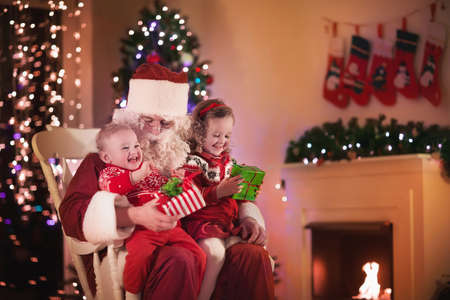 santa claus and children opening presents at fireplace kids and father in santa costume and - Santa Claus With Kids santa claus and children opening presents at fireplace kids and father in santa costume and - Santa Claus With Kids