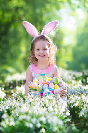 Sun flower: Kleine Mädchen, die Spaß auf Ostereiersuche. Kinder in Hasenohren und Kaninchen Kostüm. Kinder für Eier im Garten suchen. Kleinkind-Kind spielen im Freien. Kinder Lachen und Lächeln an einem Frühlingstag Lizenzfreie Bilder