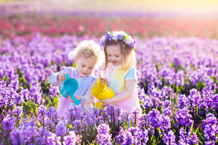 Children planting spring flowers in sunny garden. Фото со стока