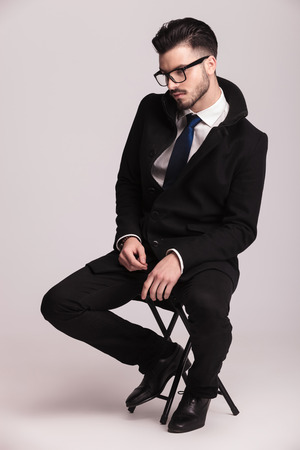 Homme élégant Cool Assis En Studio, Portant Un Jean Et Un Homme élégant Cool Assis En Studio, Portant Un Jean Et Un
