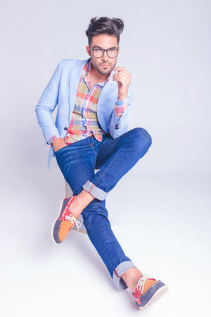 Homme élégant Cool Assis En Studio, Portant Un Jean Et Un Homme élégant Cool Assis En Studio, Portant Un Jean Et Un